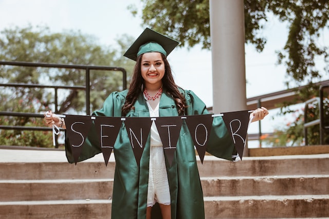 smiling person in green academic costume